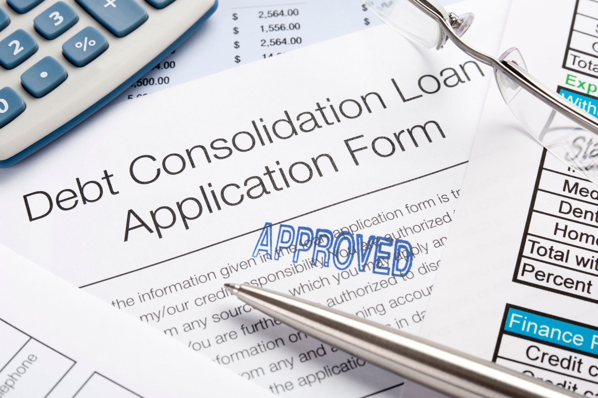 Approved Debt Consolidation Loan Application Form with pen, calc